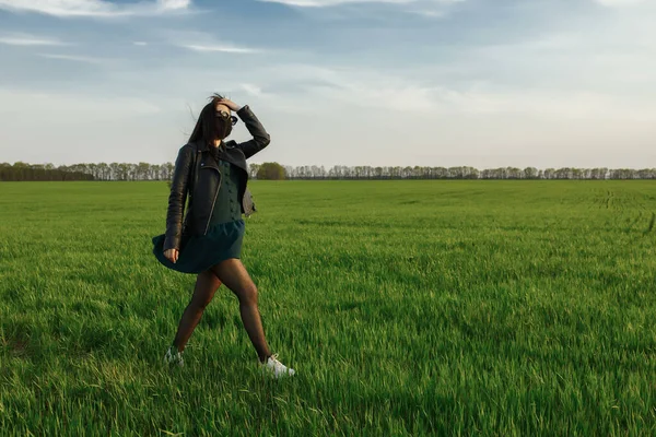 Une fille portant un masque médical court ou marche sur un champ vert. Quarantaine printemps été. coronavirus. COVID 19. Virus de la grippe, rhume — Photo