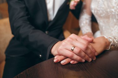 Gelin ve damat alyanslarla el ele tutuşuyorlar.