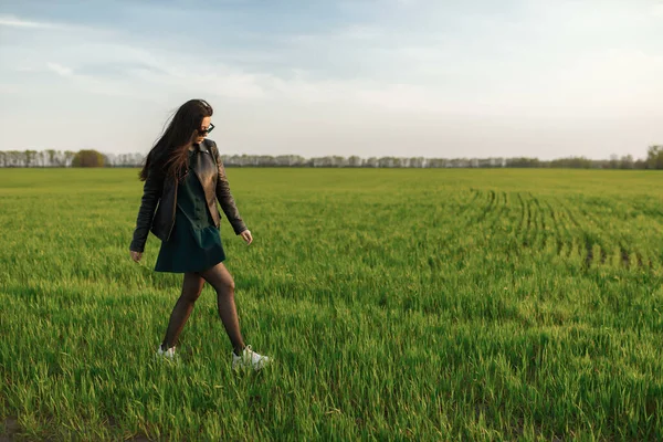 Portrait complet d'une fille élégante marchant le long d'un champ vert. Une jeune femme souriante marche dans la nature. Prairie printanière verte — Photo