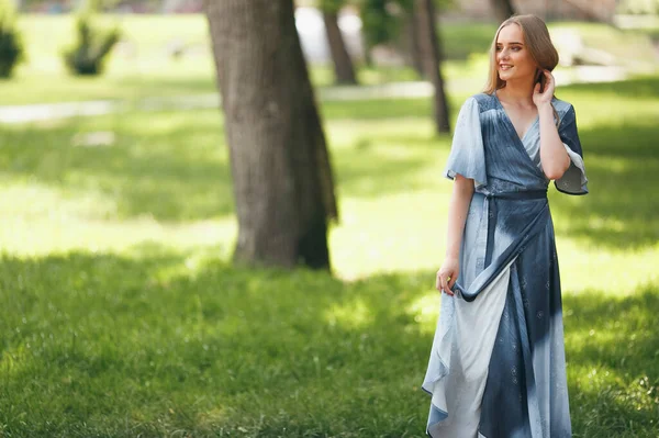 Chica con estilo posando en un vestido en un soleado parque de primavera. Alegre, feliz retrato de una hermosa chica en el verano — Foto de Stock