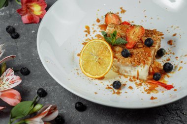 Karamel soslu Napolyon keki. Çilek, yaban mersini ve naneyle süslenmiş muhallebi ve karamel soslu lezzetli börek.