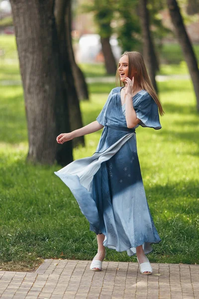 在一个阳光灿烂的春天公园里,一个时髦的女孩穿着一件衣服摆姿势.夏天，一个漂亮姑娘快乐而快乐的画像 — 图库照片