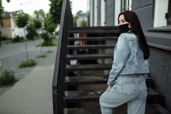 Fille dans un masque de protection sur un balcon regarde une ville vide — Photo