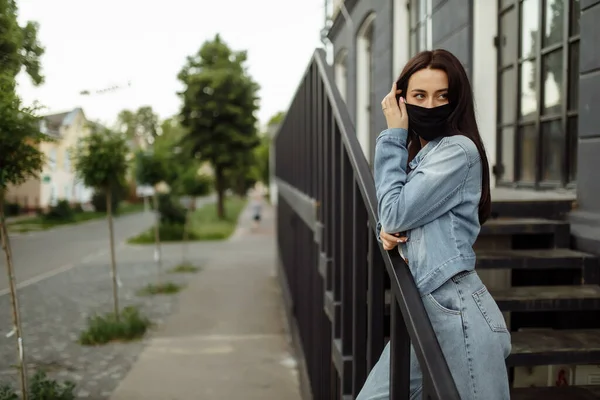 Flicka i en skyddande mask på en balkong tittar på en tom stad — Stockfoto