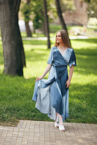 Ragazza elegante in posa in un abito in un parco primaverile soleggiato. Allegro, felice ritratto di una bella ragazza in estate — Foto Stock