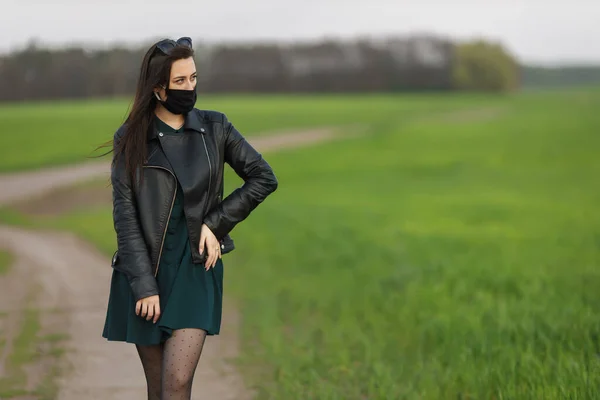 Een meisje met een medisch masker rent of loopt op een groen veld. Quarantaine lente zomer. Het coronavirus. Ik heb nummer 19. Griepvirus, verkoudheid — Stockfoto