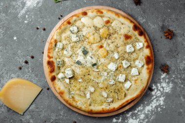 Dört peynirli pizza, İtalyan pizzası. Gri arka planda dört çeşit peynirle doldurulmuş pizza.