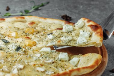 Dört peynirli pizza, İtalyan pizzası. Gri arka planda dört çeşit peynirle doldurulmuş pizza.