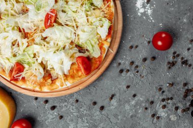 Beyaz soslu, tavuklu, parmesanlı, yumurtalı, vişneli domatesli ve ahşap arka planda taze marullu lezzetli pizza Sezar tarzı. Pizzacı menüsü. Lezzetli pizza Sezar.
