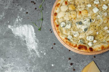 Dört peynirli pizza, İtalyan pizzası. Gri arka planda dört çeşit peynirle doldurulmuş pizza.