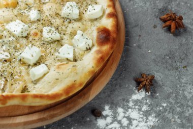 Dört peynirli pizza, İtalyan pizzası. Gri arka planda dört çeşit peynirle doldurulmuş pizza.
