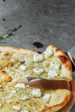 Dört peynirli pizza, İtalyan pizzası. Gri arka planda dört çeşit peynirle doldurulmuş pizza.