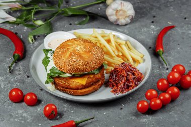 Patates kızartmalı tavuk burger ve eski beton arka planda salata..