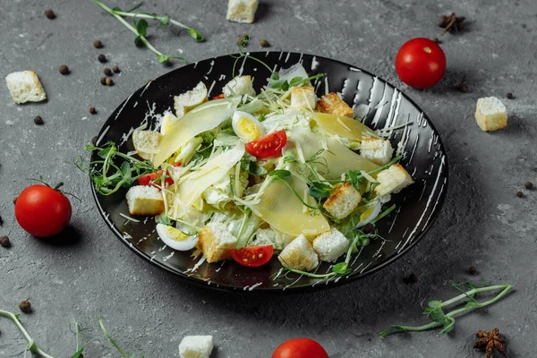 Gri arka planda siyah tabakta taze Sezar salatası. Üst görünüm.