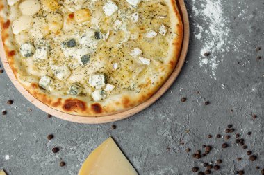 Dört peynirli pizza, İtalyan pizzası. Gri arka planda dört çeşit peynirle doldurulmuş pizza.