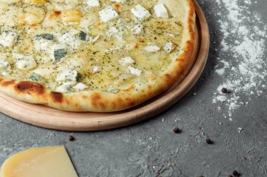 Dört peynirli pizza, İtalyan pizzası. Gri arka planda dört çeşit peynirle doldurulmuş pizza.