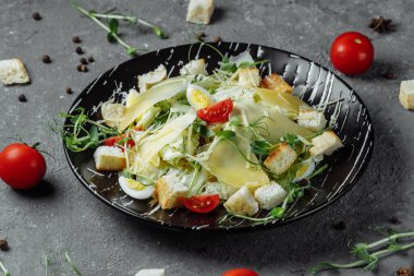 Gri arka planda siyah tabakta taze Sezar salatası. Üst görünüm.