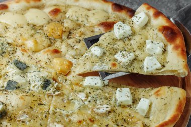 Dört peynirli pizza, İtalyan pizzası. Gri arka planda dört çeşit peynirle doldurulmuş pizza.