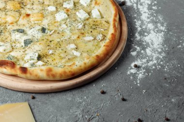 Dört peynirli pizza, İtalyan pizzası. Gri arka planda dört çeşit peynirle doldurulmuş pizza.