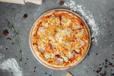 Peynirli, soslu, jambonlu, pastırmalı, gri arka planda salamlı pizza..