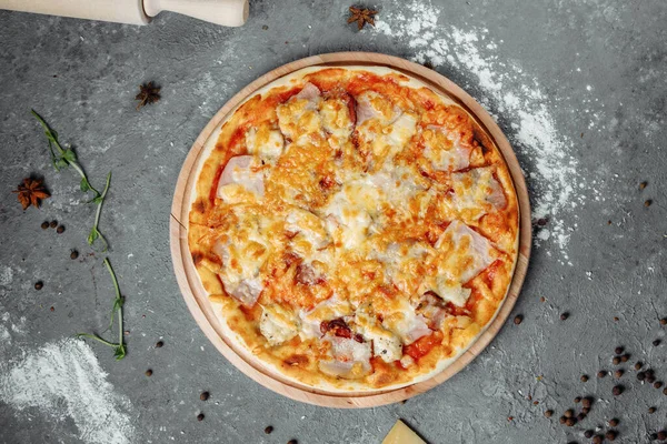 Peynirli, soslu, jambonlu, pastırmalı, gri arka planda salamlı pizza..