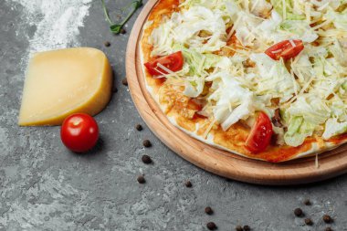 Beyaz soslu, tavuklu, parmesanlı, yumurtalı, vişneli domatesli ve ahşap arka planda taze marullu lezzetli pizza Sezar tarzı. Pizzacı menüsü. Lezzetli pizza Sezar.