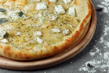 Dört peynirli pizza, İtalyan pizzası. Gri arka planda dört çeşit peynirle doldurulmuş pizza.