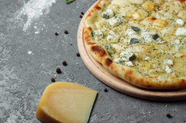Dört peynirli pizza, İtalyan pizzası. Gri arka planda dört çeşit peynirle doldurulmuş pizza.