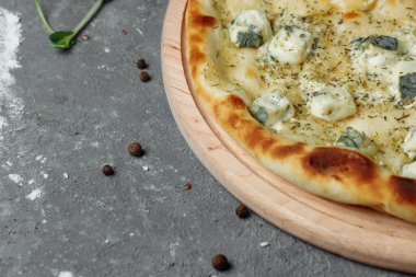 Dört peynirli pizza, İtalyan pizzası. Gri arka planda dört çeşit peynirle doldurulmuş pizza.