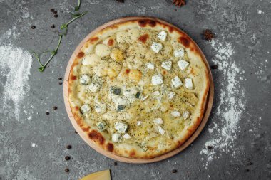 Dört peynirli pizza, İtalyan pizzası. Gri arka planda dört çeşit peynirle doldurulmuş pizza.