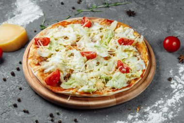 Beyaz soslu, tavuklu, parmesanlı, yumurtalı, vişneli domatesli ve ahşap arka planda taze marullu lezzetli pizza Sezar tarzı. Pizzacı menüsü. Lezzetli pizza Sezar.