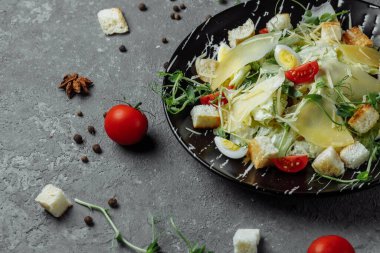 Gri arka planda siyah tabakta taze Sezar salatası. Üst görünüm.