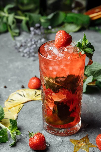 Jordgubbe Mojito. Kall sommar mojito cocktail med jordgubbar, mynta, citron och is i ett glas på ett bord. på en mörk bakgrund — Stockfoto