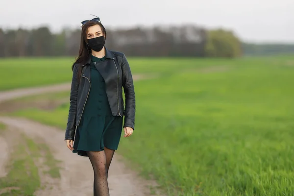 Dívka v lékařské masce běhá nebo kráčí po zeleném poli. Karanténní jaro. coronavirus. COVID 19. Virus chřipky, nachlazení — Stock fotografie