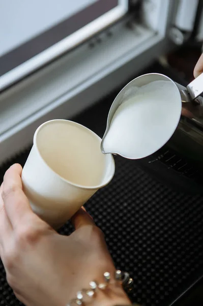Barista draws milk over a coffee - making latte art for cappuccino
