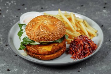 Patates kızartmalı tavuk burger ve eski beton arka planda salata..