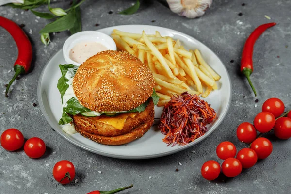 Patates kızartmalı tavuk burger ve eski beton arka planda salata..