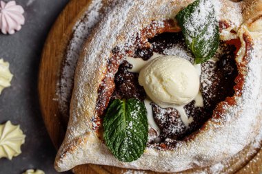Naneli ve bisküviyle süslenmiş dondurma, çikolata ve kuru erikli Adjarian tatlı khachapuri. Mavi bir tahtada