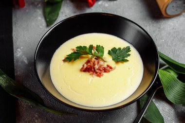 Bir kase lezzetli peynir kremalı çorba ve gri bir arka planda pastırma..