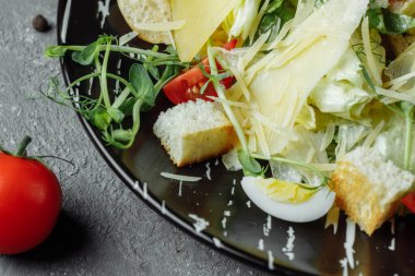 Gri arka planda siyah tabakta taze Sezar salatası. Üst görünüm.