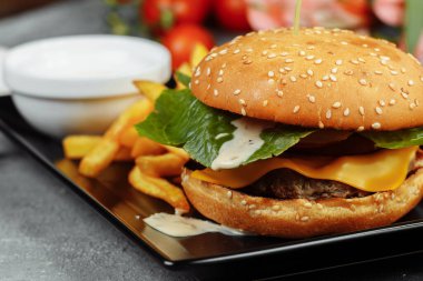 Pirzola, peynir ve domatesli hamburger. Patates kızartması ve hamburger sosuyla..