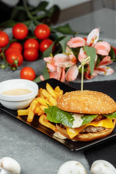 Pirzola, peynir ve domatesli hamburger. Patates kızartması ve hamburger sosuyla..