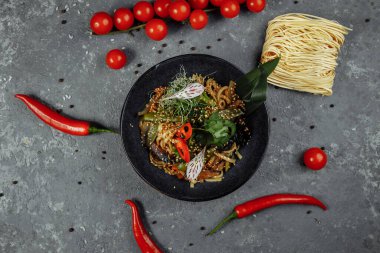 Kızarmış erişte ve sebze, siyah kasede. Lezzetli, besleyici Asya yemekleri..