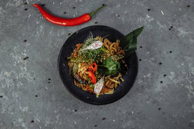 Kızarmış erişte ve sebze, siyah kasede. Lezzetli, besleyici Asya yemekleri..