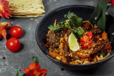 Erişteler, dana eti ve sebzeler gri masada..