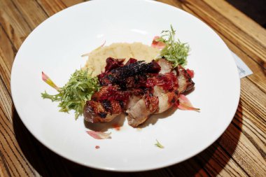 Ahşap bir masada yeşil salatalı ızgara domuz bifteği..