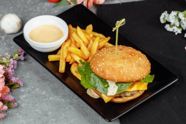 Pirzola, peynir ve domatesli hamburger. Patates kızartması ve hamburger sosuyla..