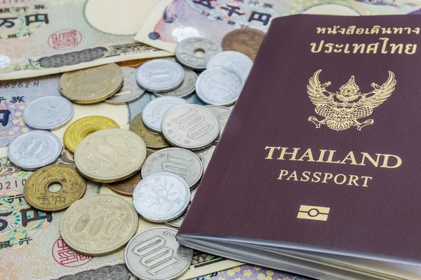 Closeup of Japanese Yen banknotes and Japanese Yen coin with Thailand passport. financial money and travel concept and business copy space background .