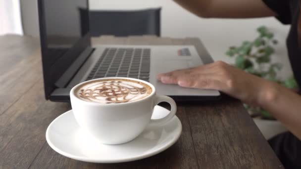 年轻妇女使用笔记本电脑在房间咖啡馆或餐馆或家庭或办公室与白色杯子咖啡放松 — 图库视频影像