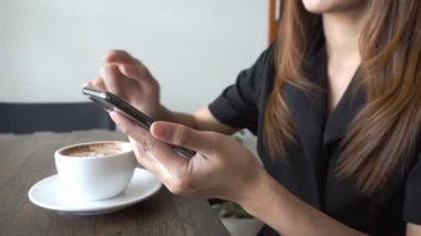 Genç kadın kullanma smartphone vasıl oda kafe ya da restoran veya ev ya da ofis beyaz fincan kahve ile rahatla